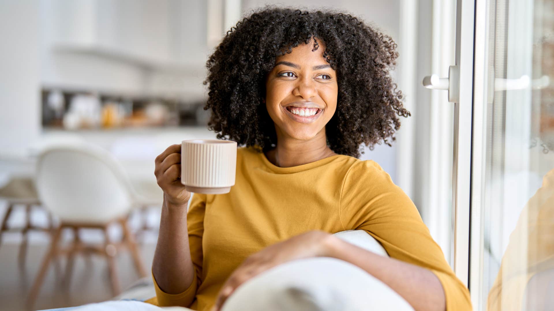 Woman smiling and drinking from a coffee mug.