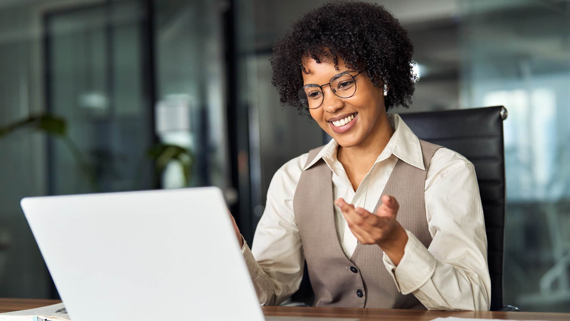 Woman smiling and talking to someone on her laptop.