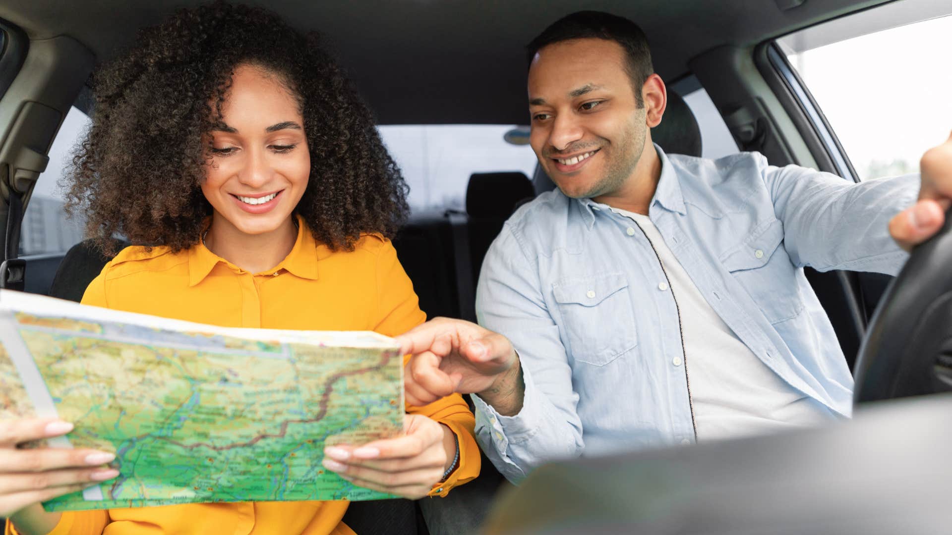 Couple driving and navigating with a paper map. 