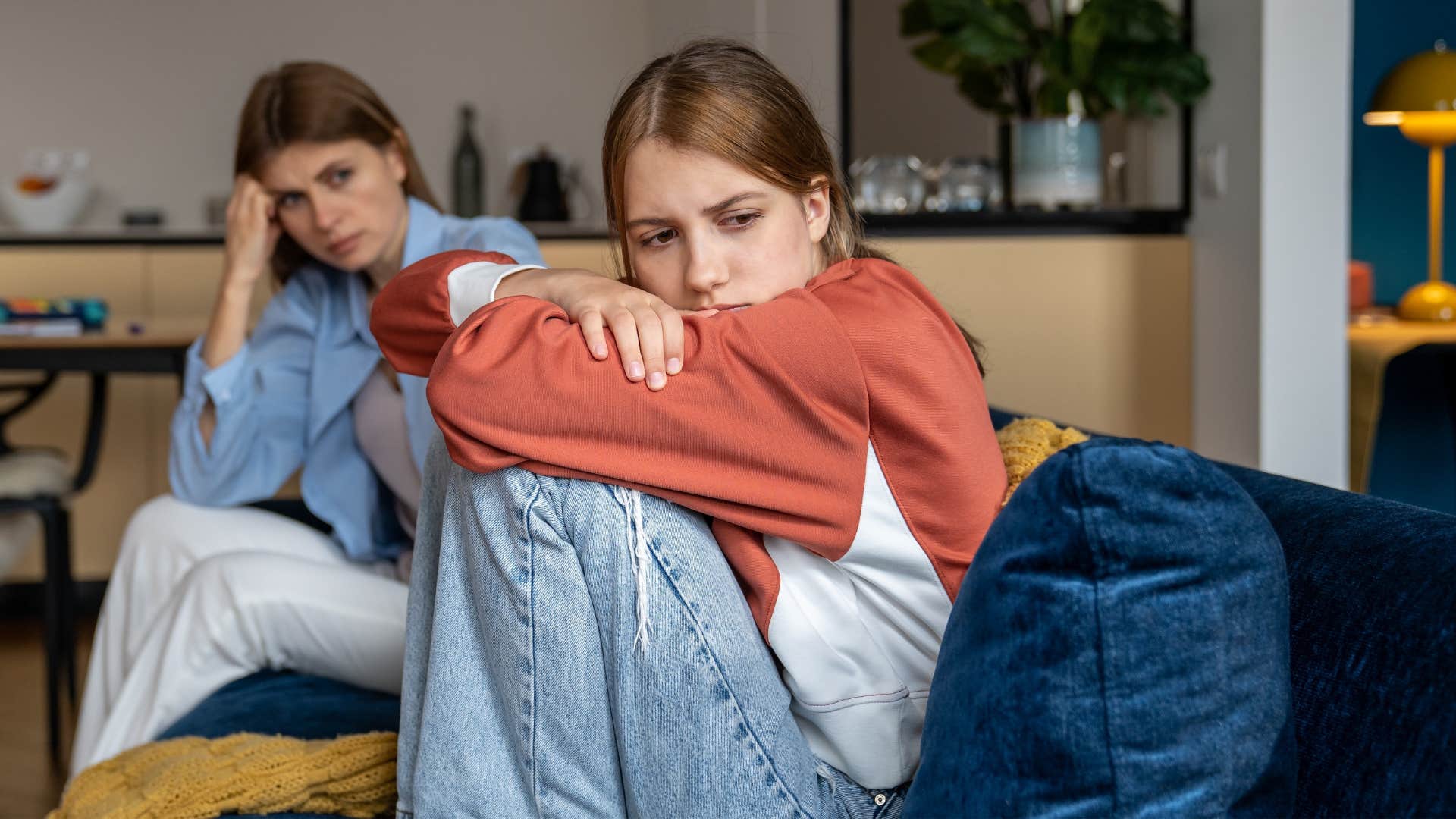 Upset teenage girl sitting in front of her mother.