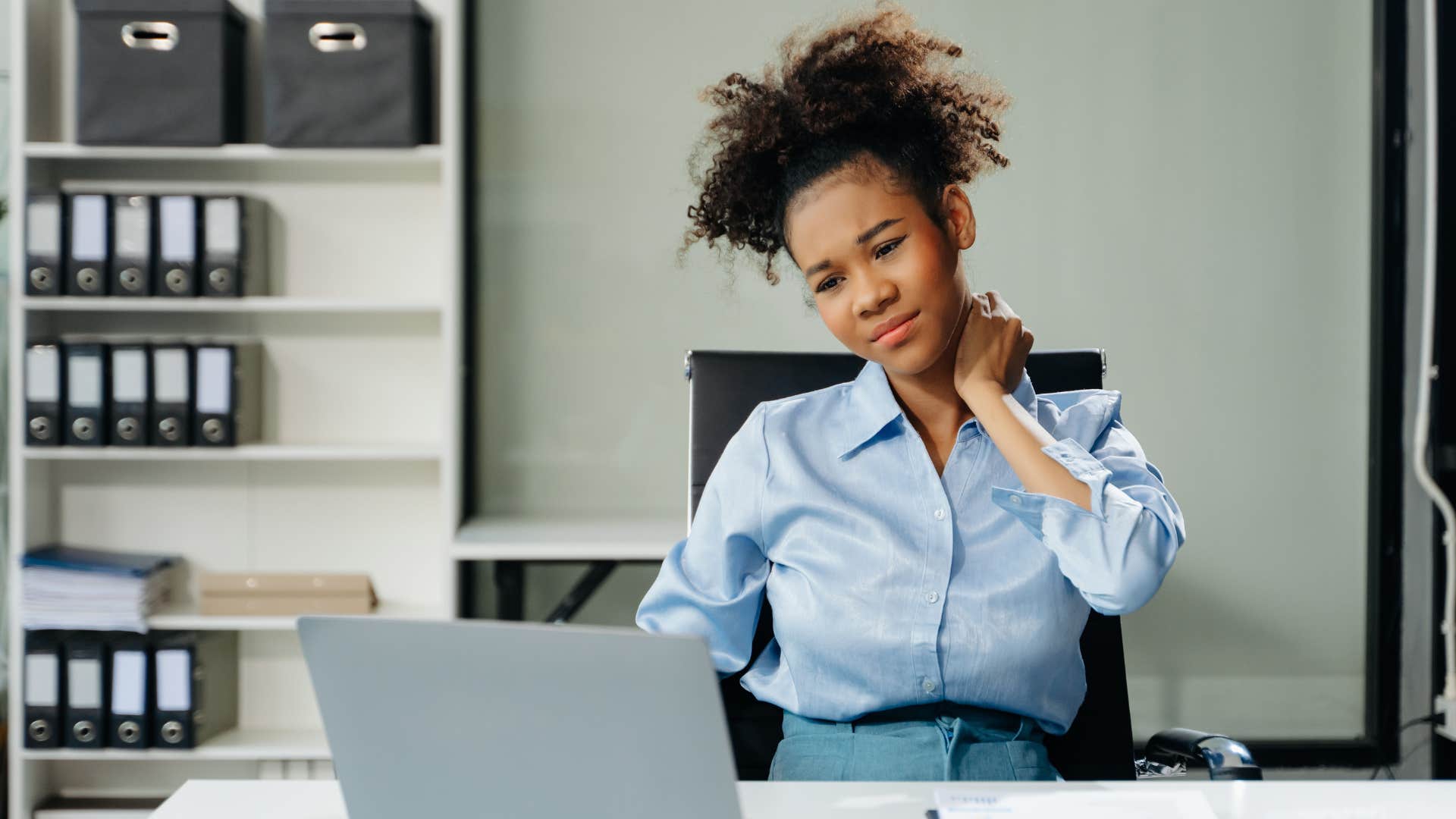 Woman holding her neck looking uncomfortable at work