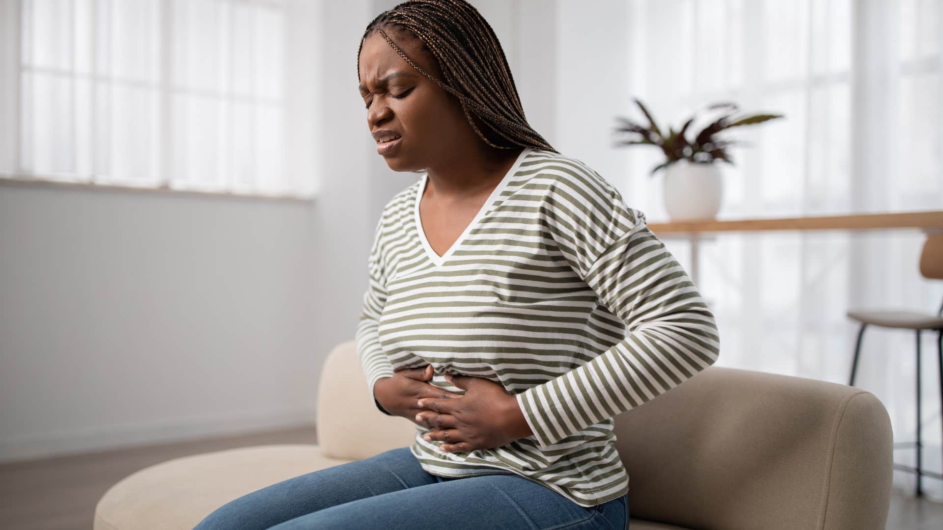 Upset woman holding her stomach on the couch