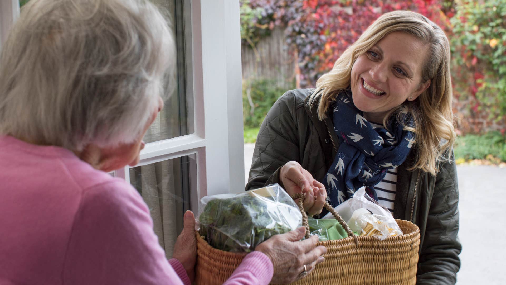 Smiling woman giving a basket of food to her neighbor