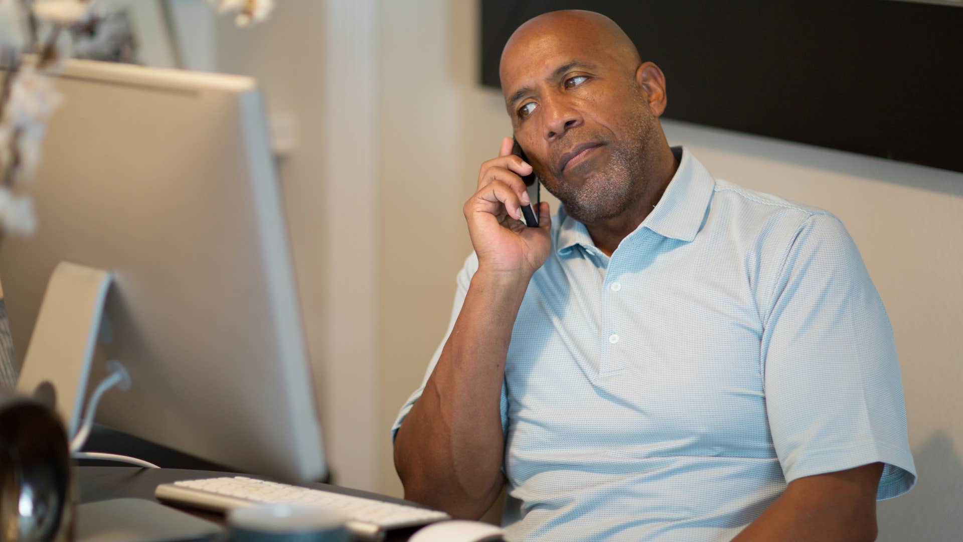 Older man looking annoyed talking on the phone.