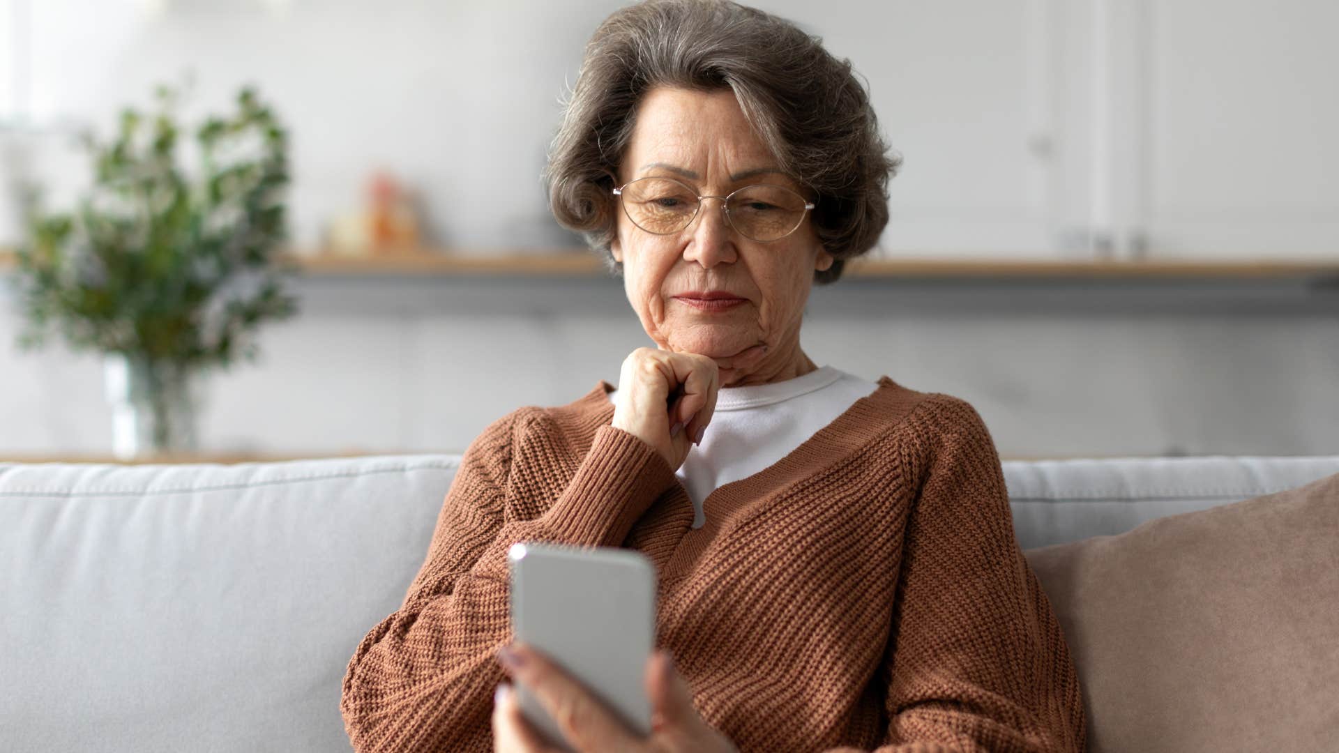 Woman looking upset staring at her phone.