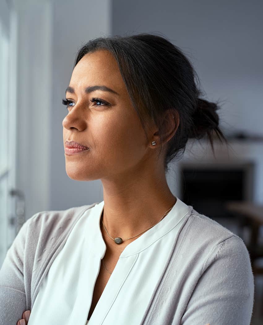 Motivated woman thinks deeply while looking out window 