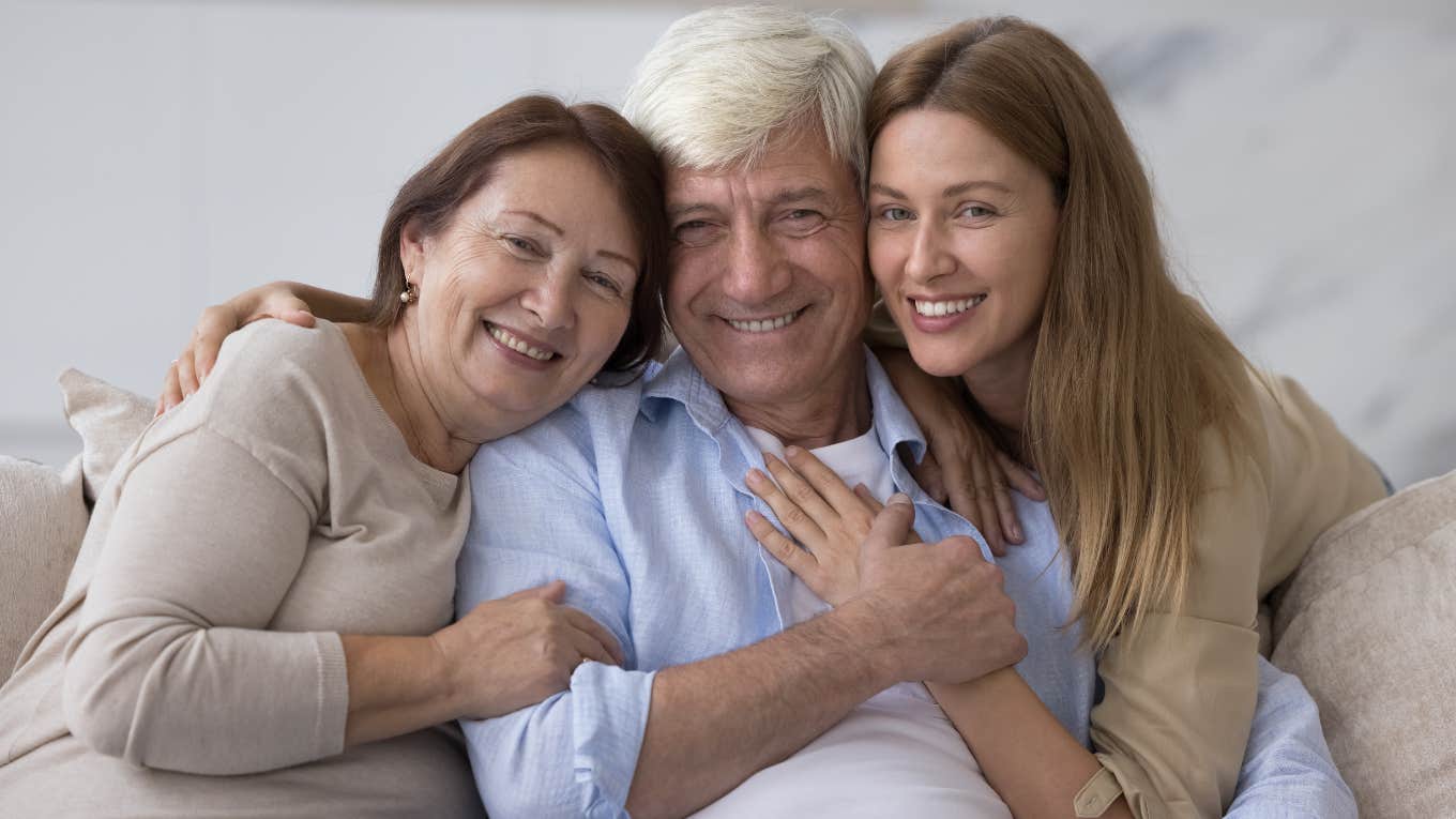 mother father and daughter smiling and embracing