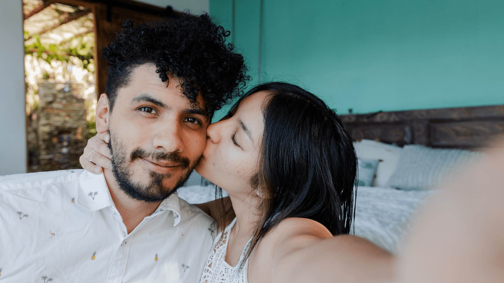 woman kissing man on cheek taking selfie