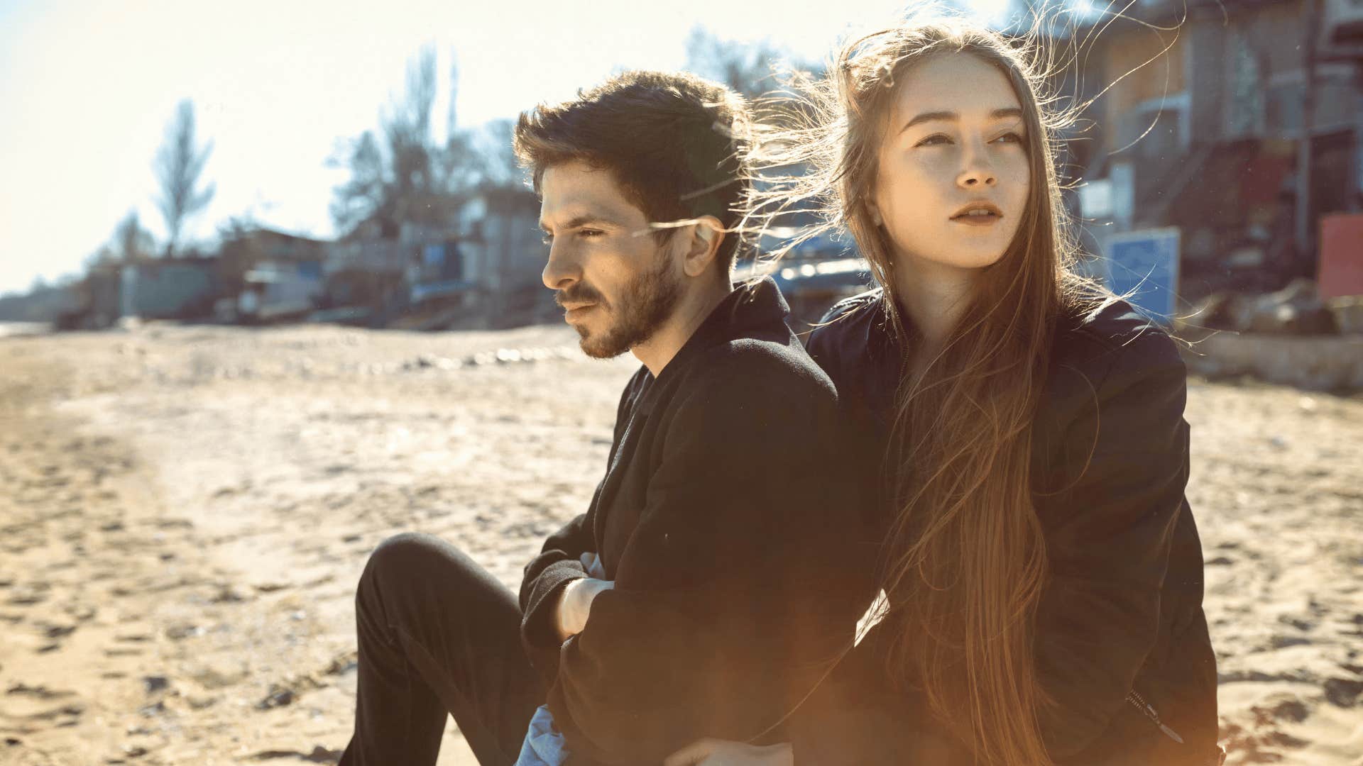 sad looking couple sitting on the beach