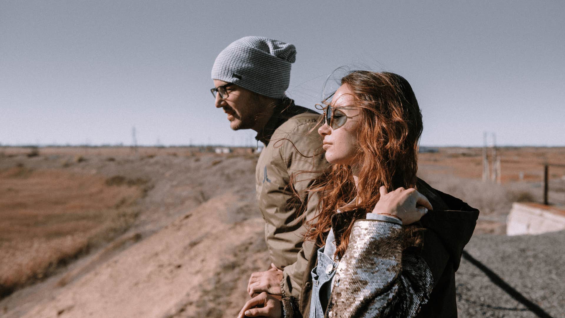 man in hat and woman next to him looking off into the distance