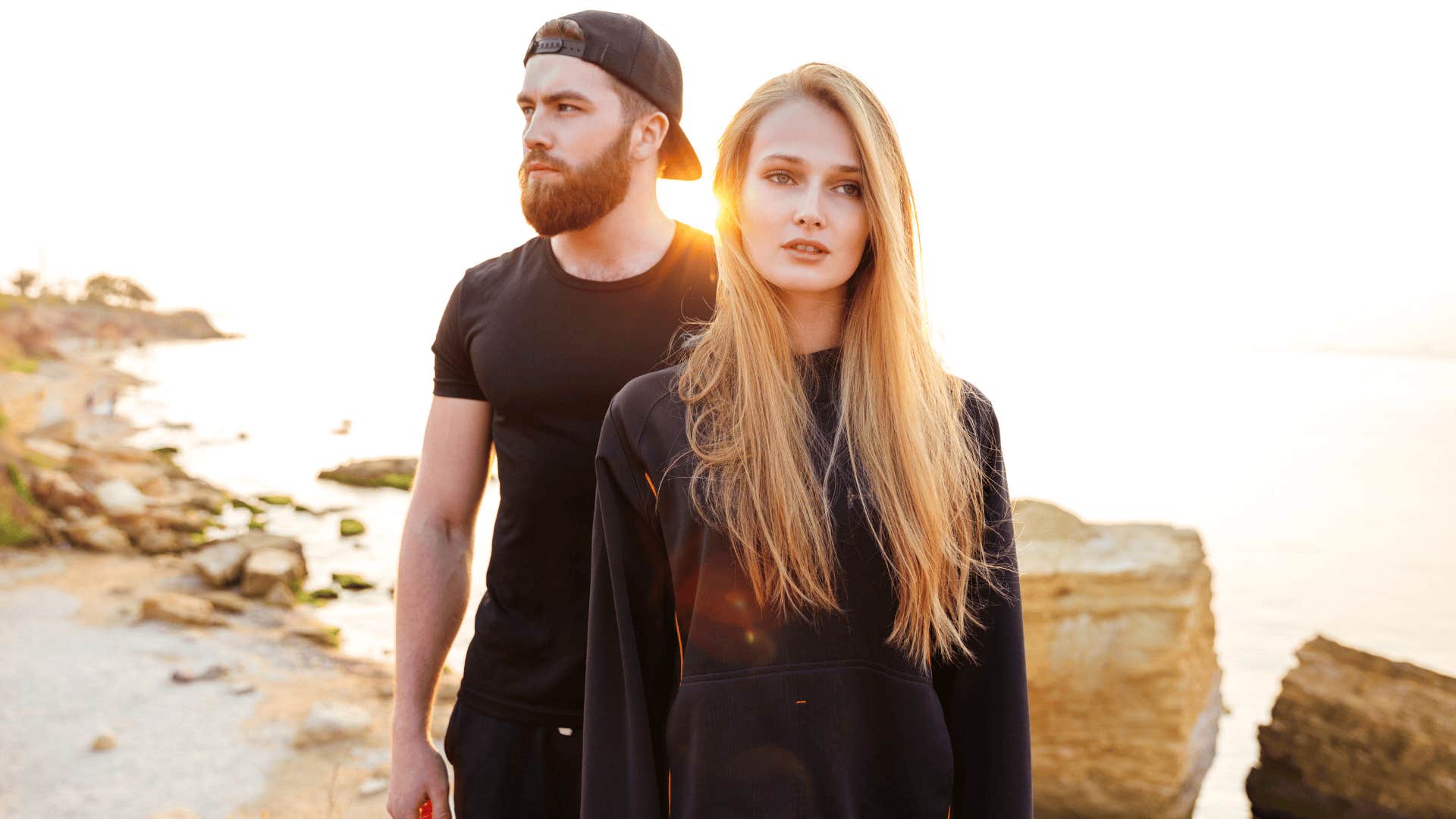 woman and man in black on the beach walking away from each other