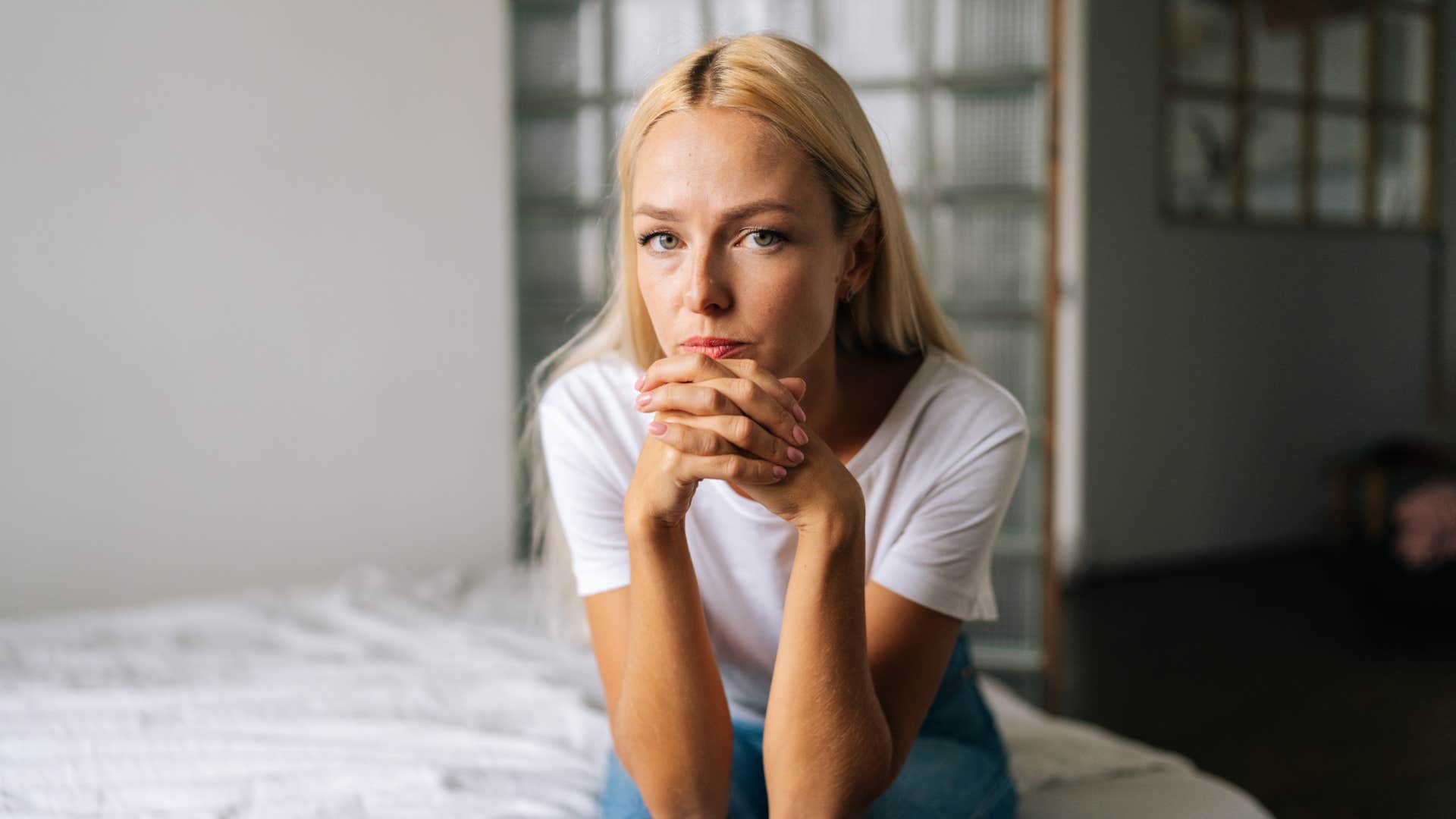 Close-up portrait of pensive young blonde woman sitting alone