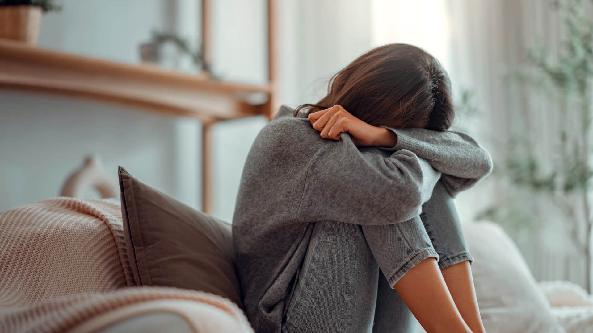 sad young woman sitting on couch in the living room at home