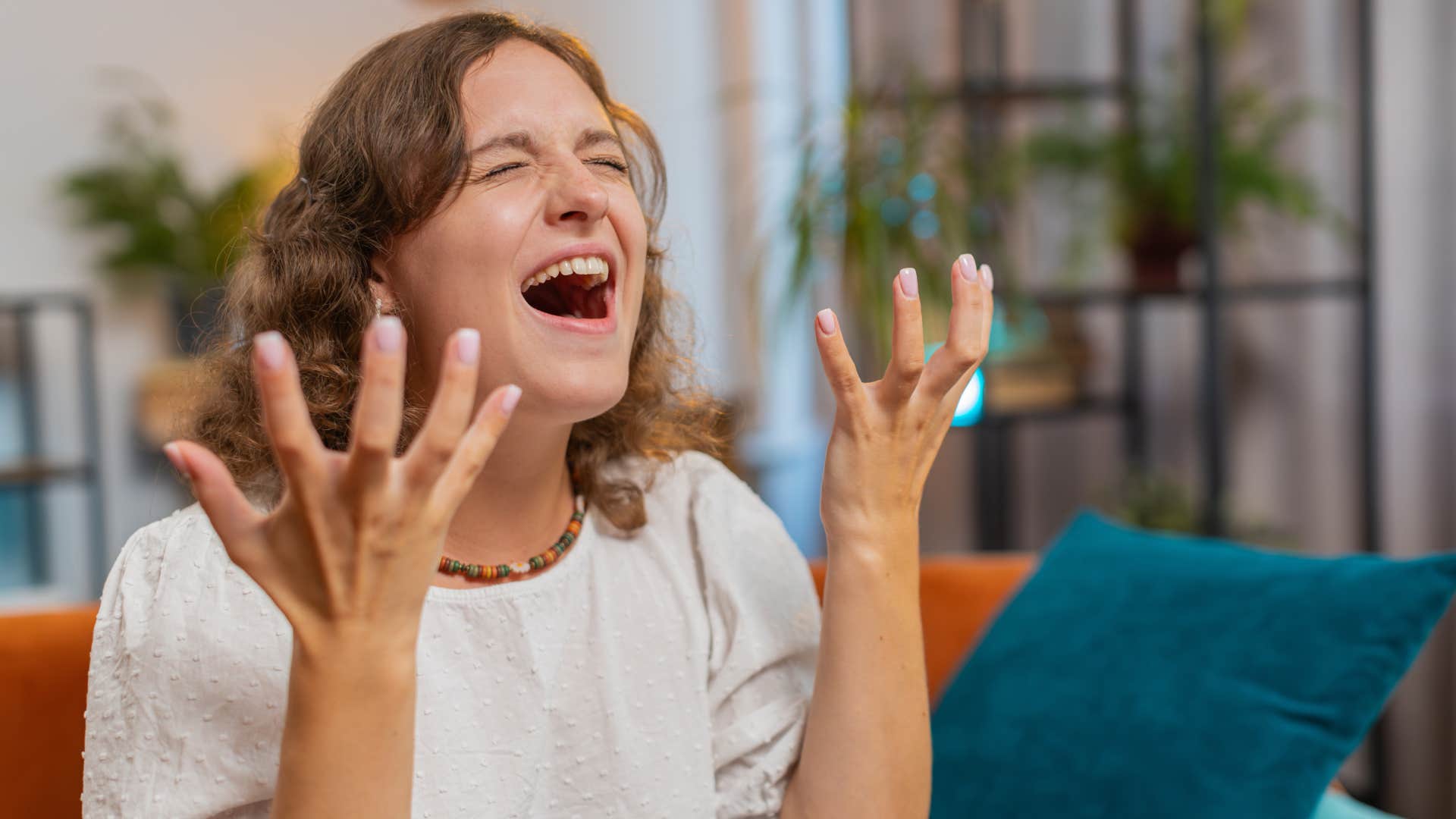 woman having breakdown on couch at home with hands in the air