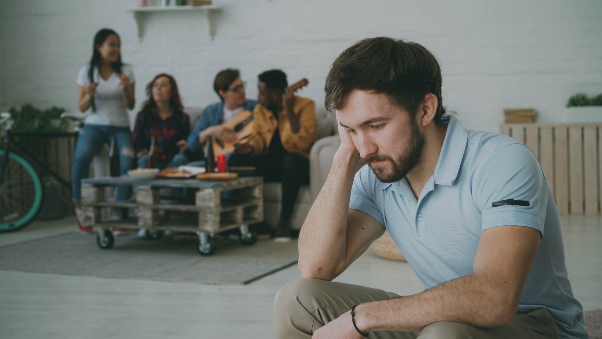 guy feels upset and isolated while his friends celebrating party at home