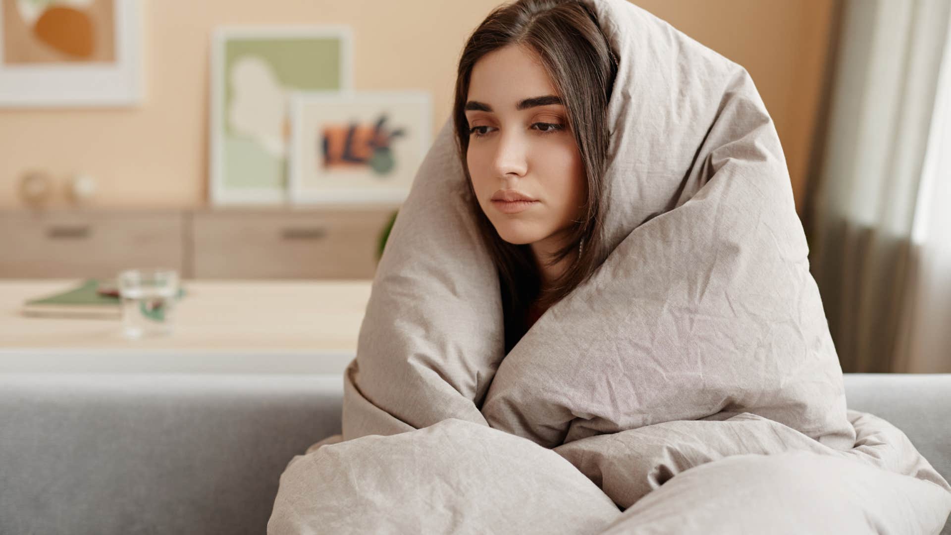 young woman wrapped in blankets at home