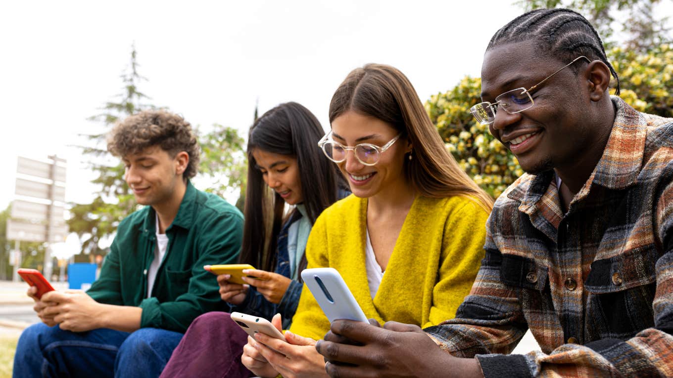 Group of teenage college friend students ignoring each other looking at mobile phone.