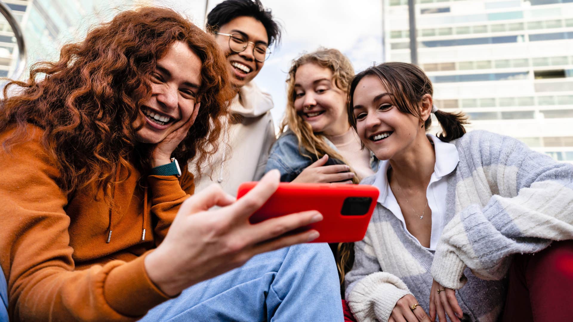 Gen Z friends smiling and looking at a phone together