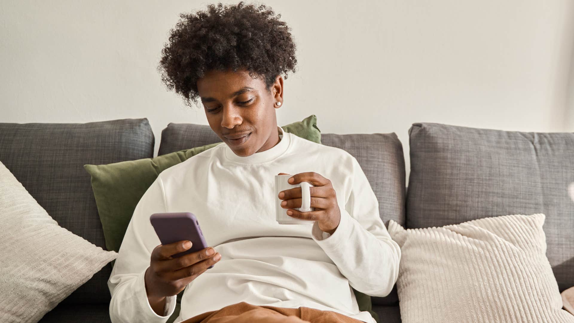 Gen Z person drinking coffee and scrolling on their phone