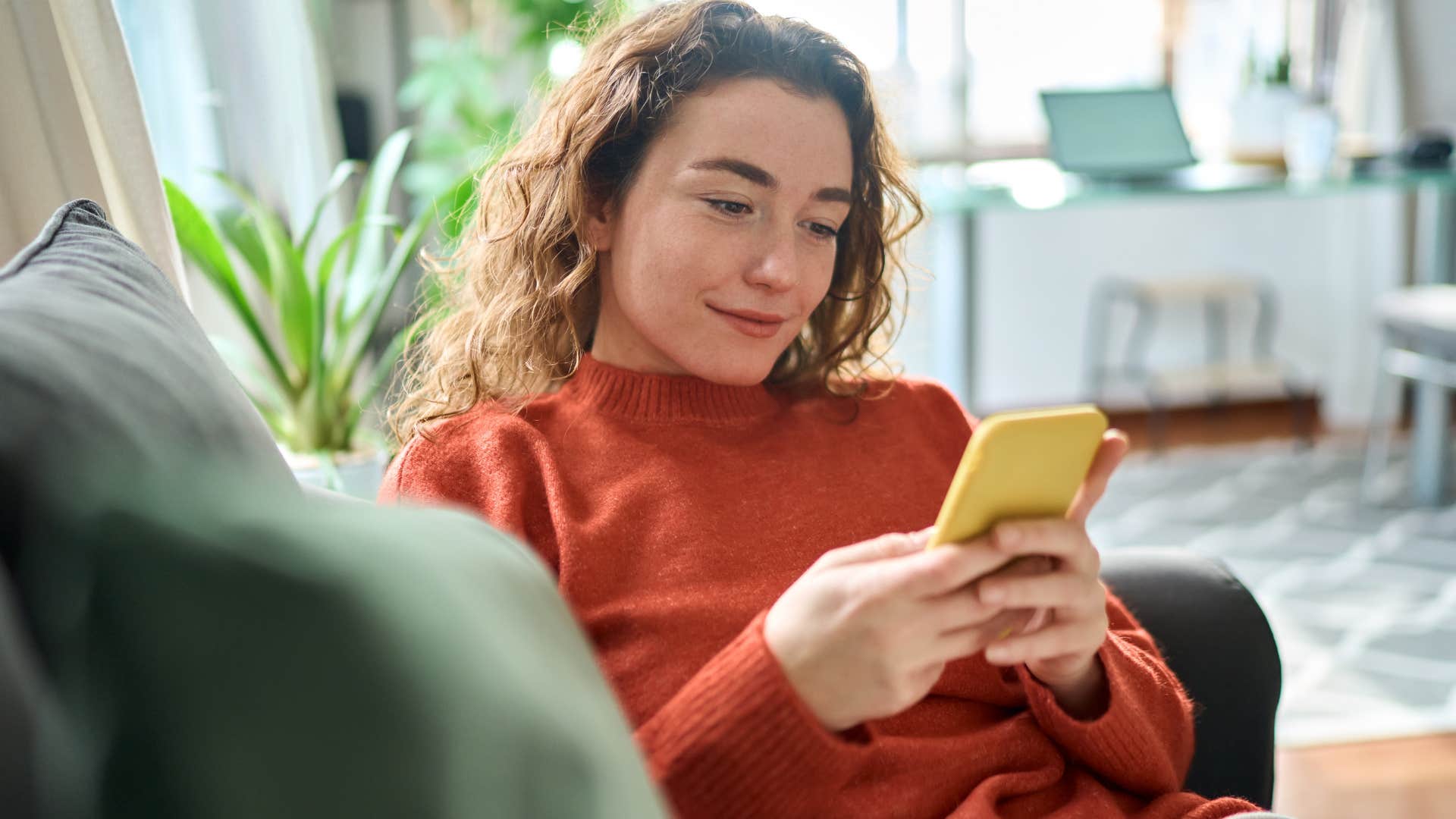 Gen Z woman smiling and texting on her phone