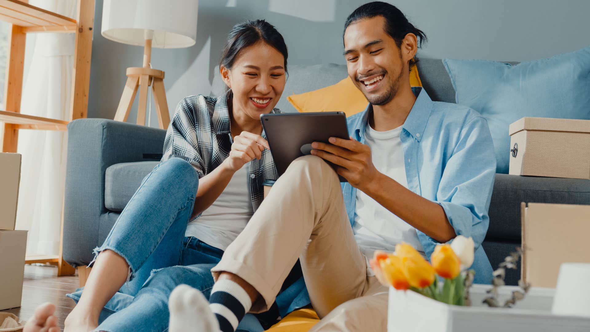 Couple smiling and sitting around moving boxes