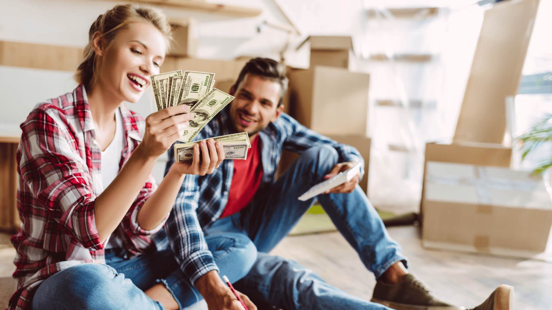 young couple with calculator and dollar banknotes counting money