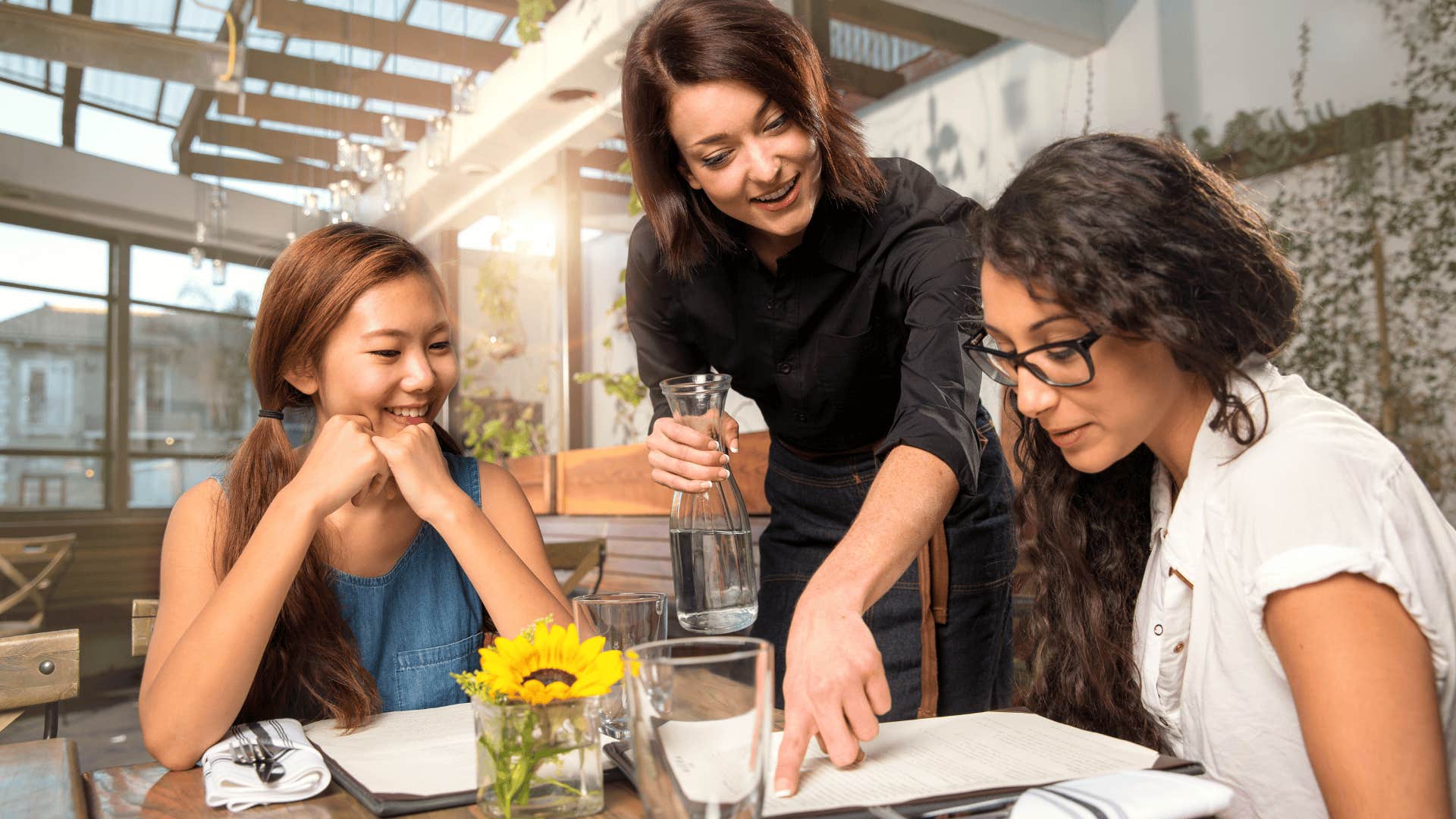 Waitress server helping client patron customer with menu order on sunny patio