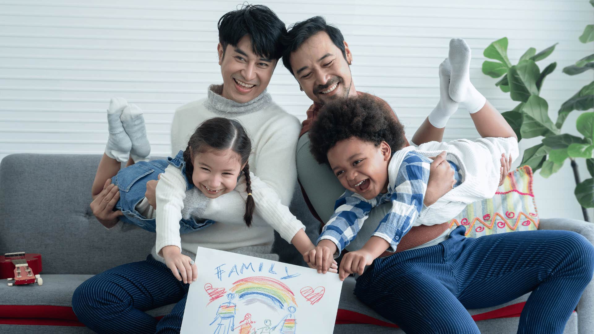 Loving parents play with two children on couch