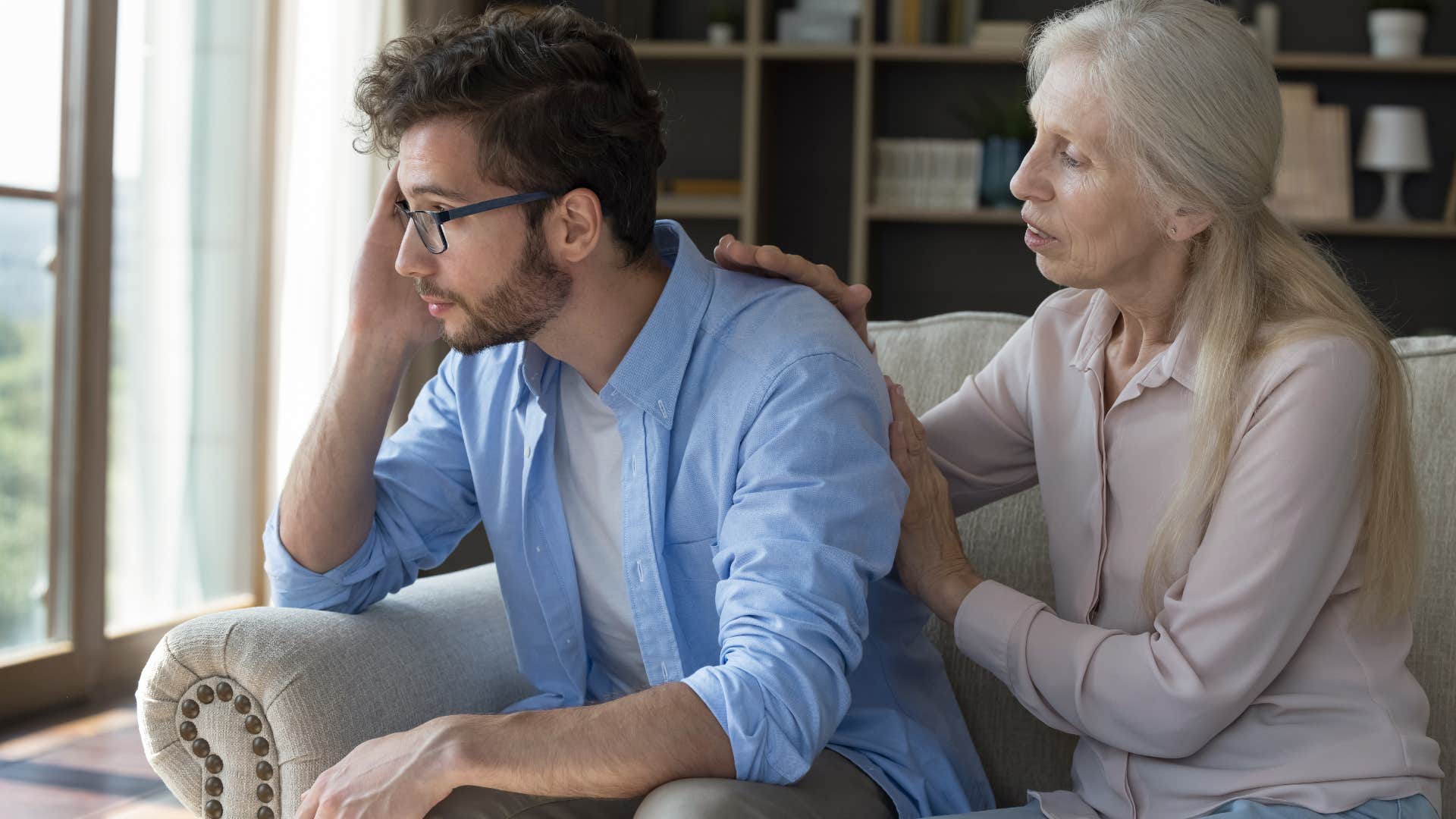 Woman comforting her upset adult son.