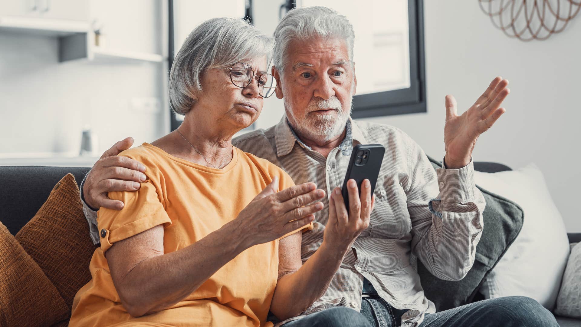 Grandparents looking upset staring at a cellphone