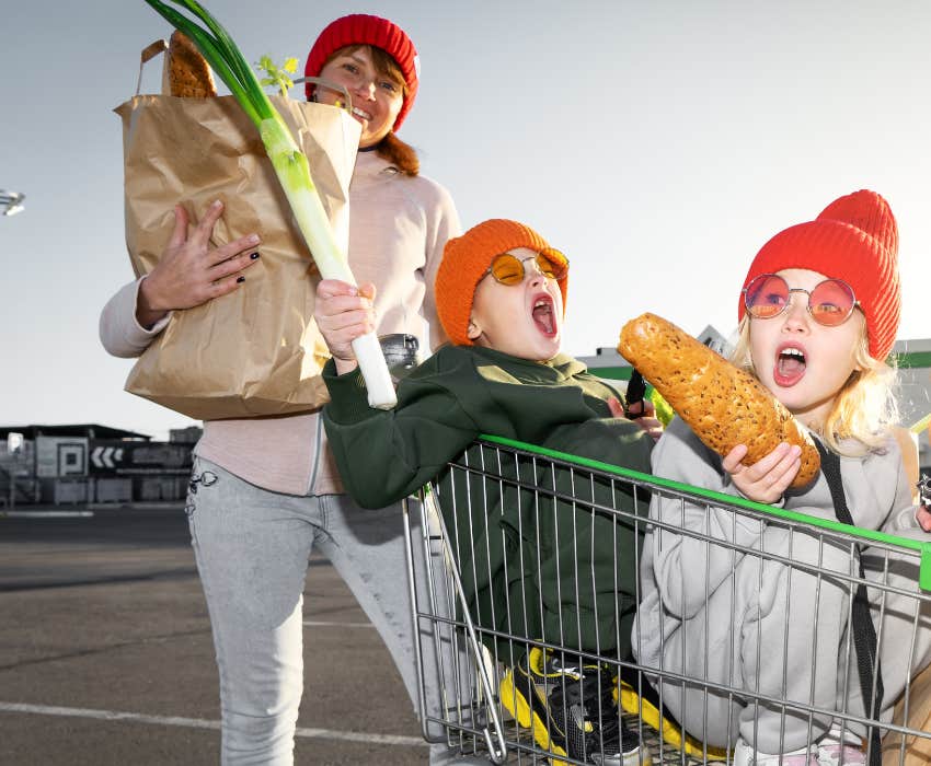 Mom rolls a boy and a girl in the grocery cart near the supermarket