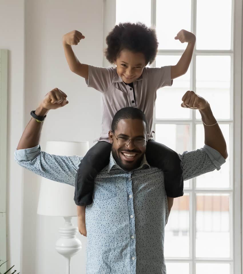 Child spend time on father's shoulders both make strong arms pose