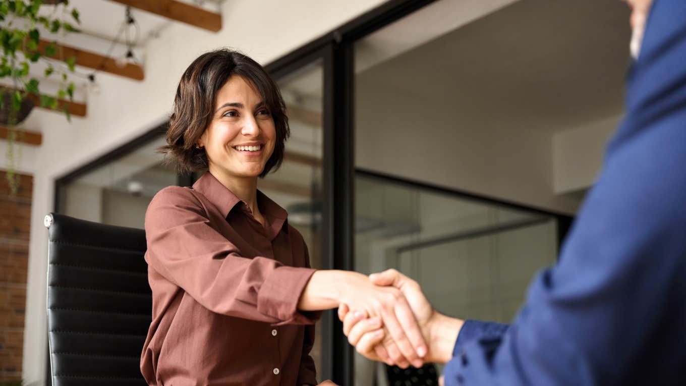 Happy young business woman bank manager handshaking client at meeting