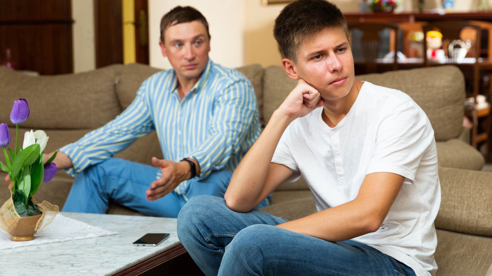 dad and son sitting on couch arguing