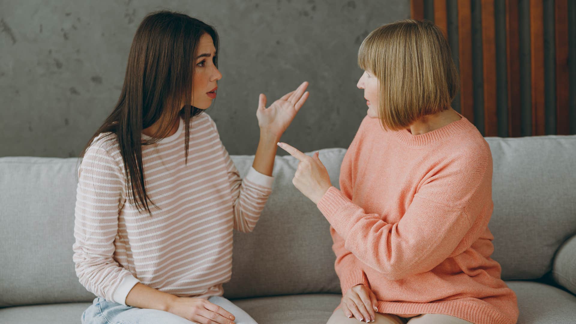 mom and adult daughter sitting on couch arguing