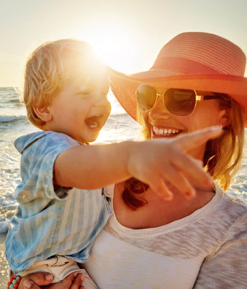 Smiling mother holds happy pointing toddler