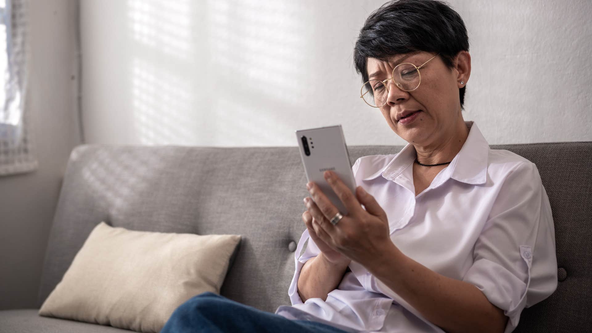 Woman looking upset texting on her phone.