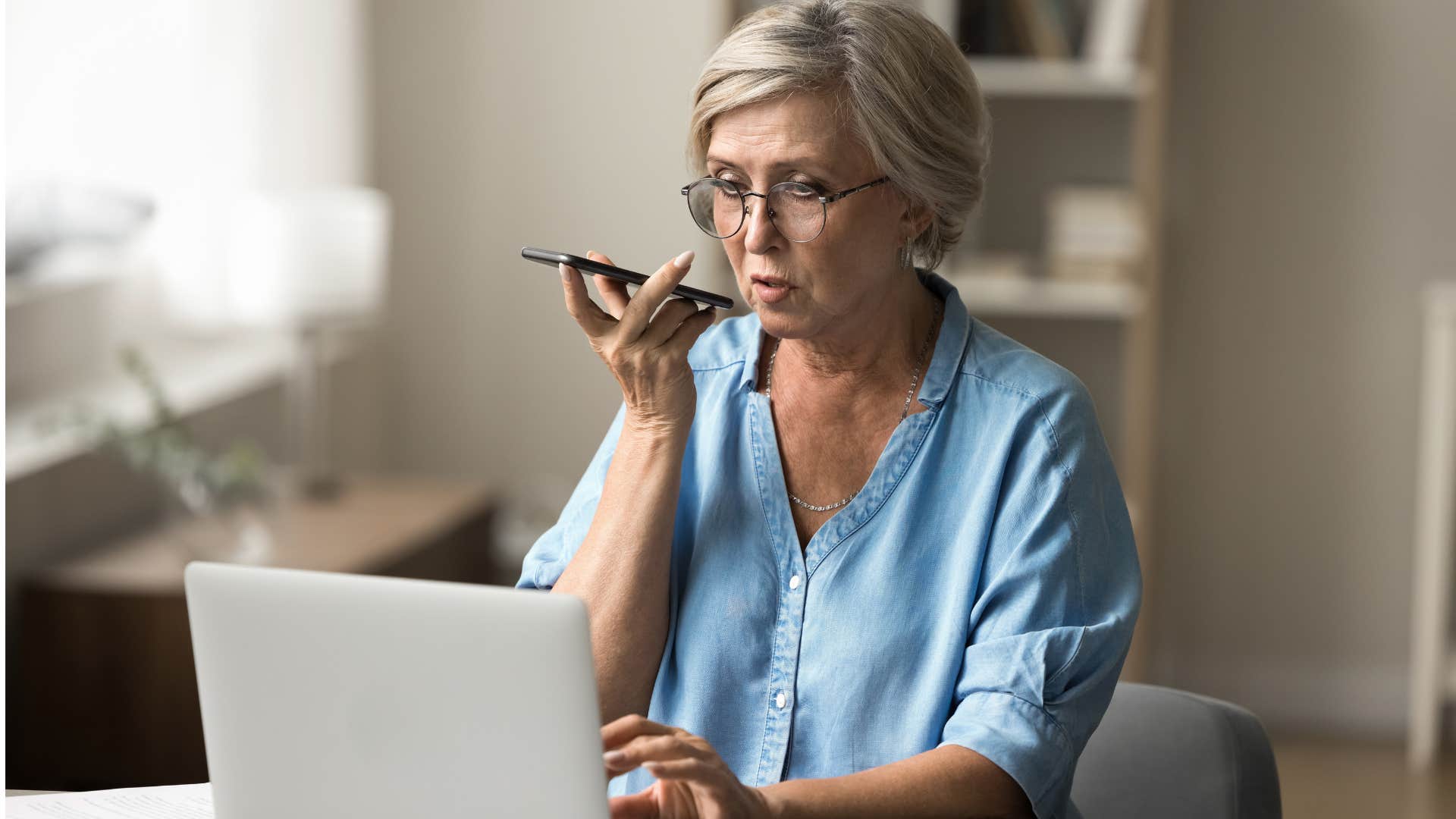 Woman talking on the phone and typing on her laptop.