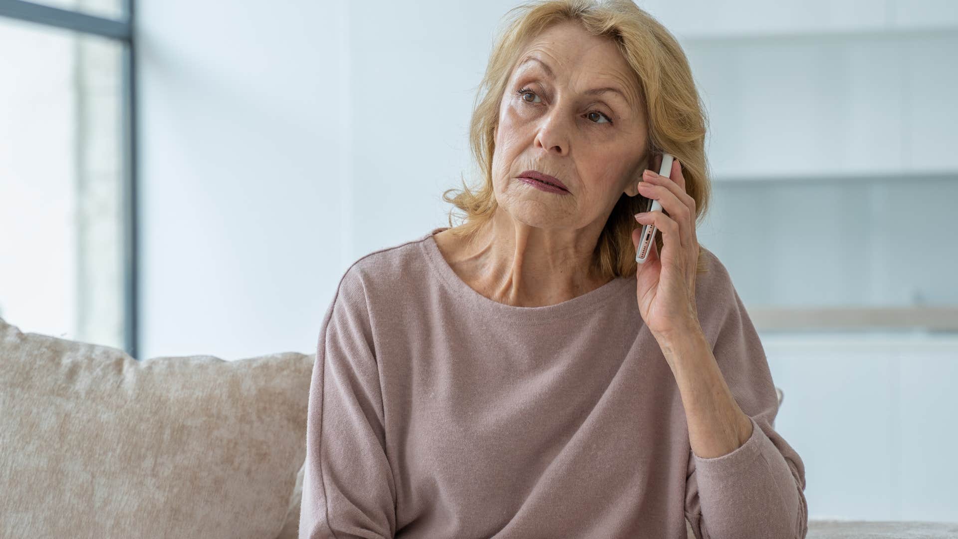 Woman looking upset talking on her phone.