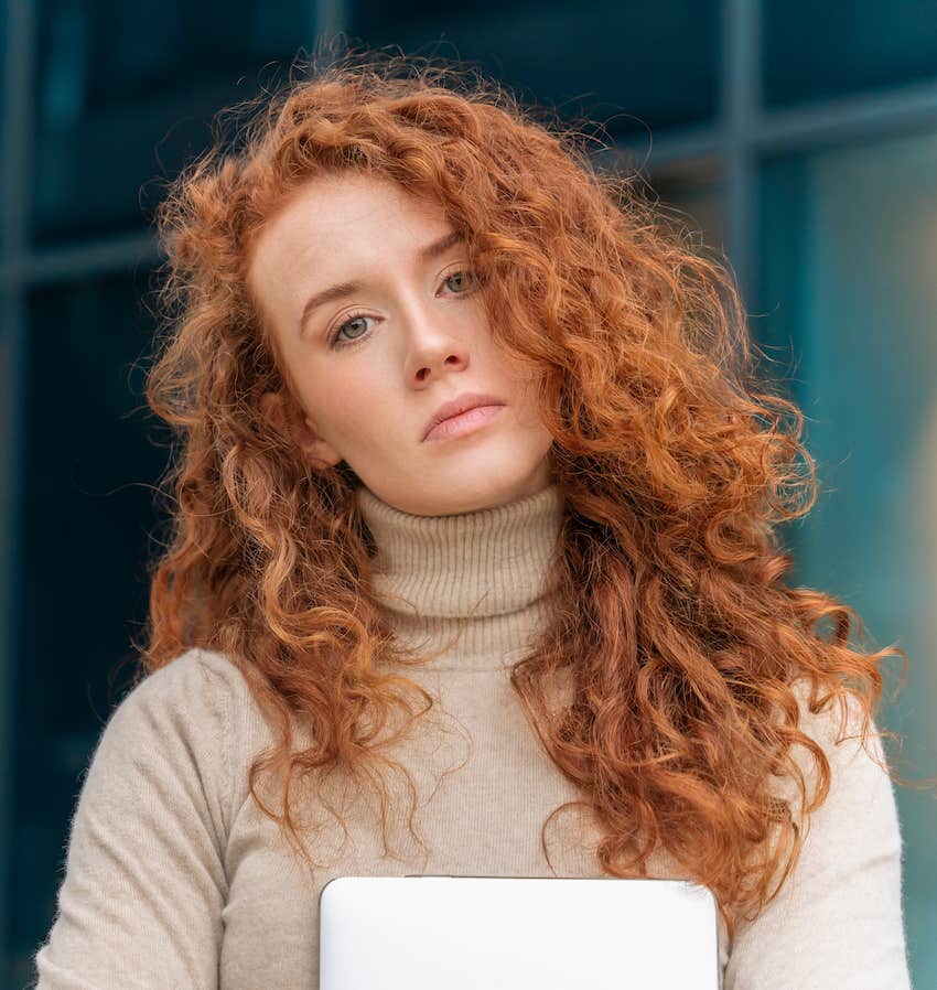 Dissatisfied woman holding papers tilts head to side