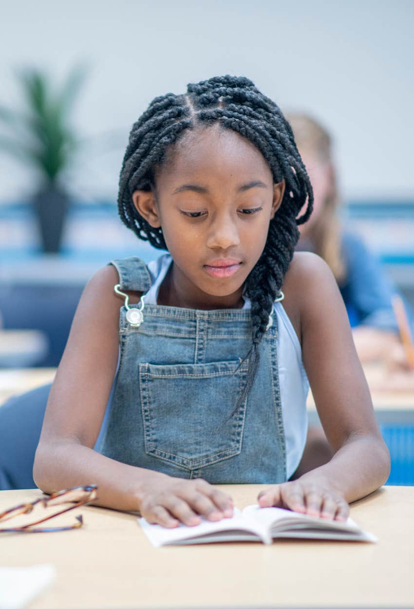 young student reading at her desk in classroom