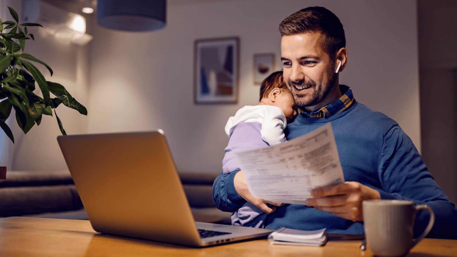 dad holding baby while trying to work