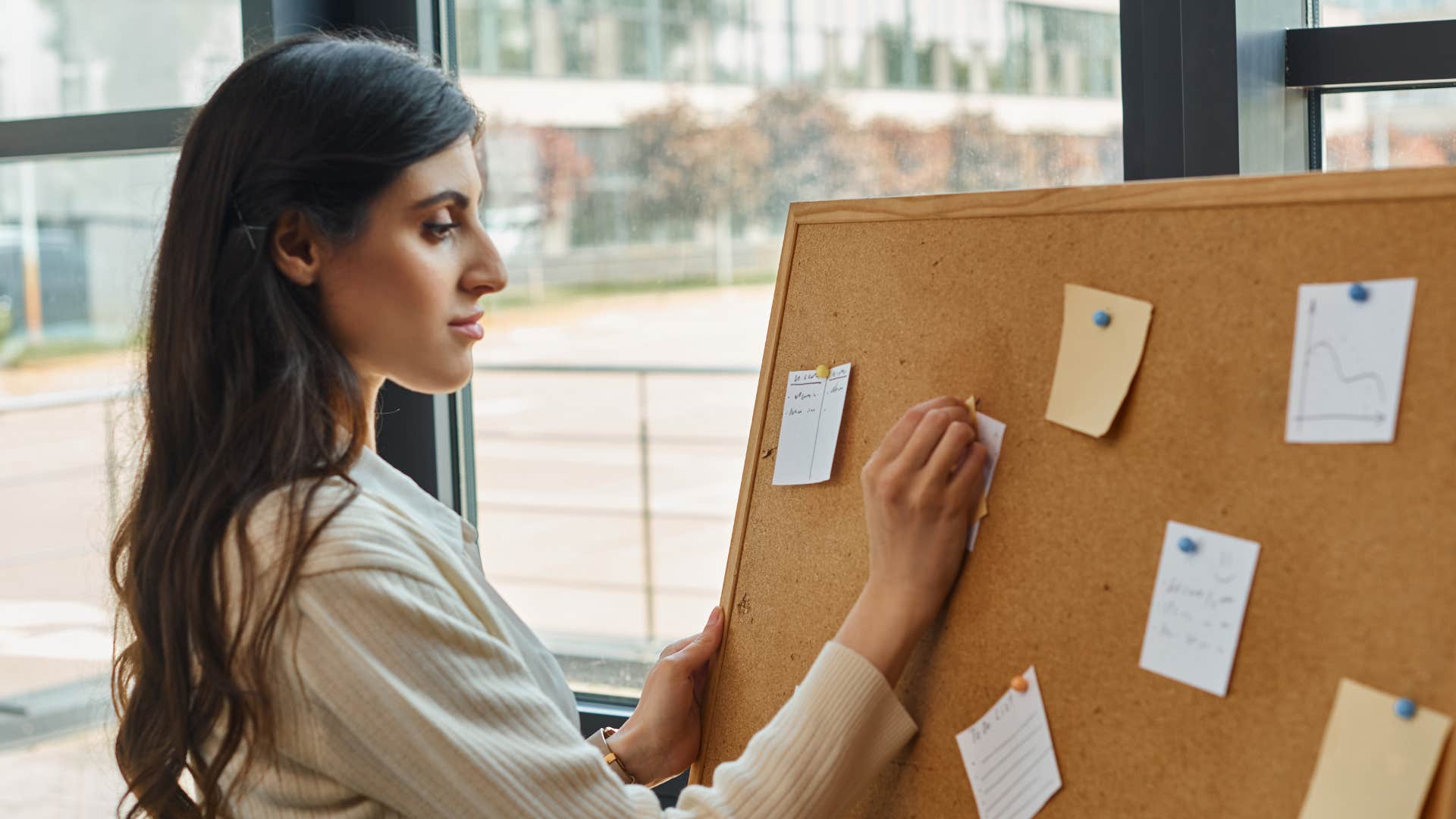 A female entrepreneur stands confidently in front of a board filled with strategic plans and ideas