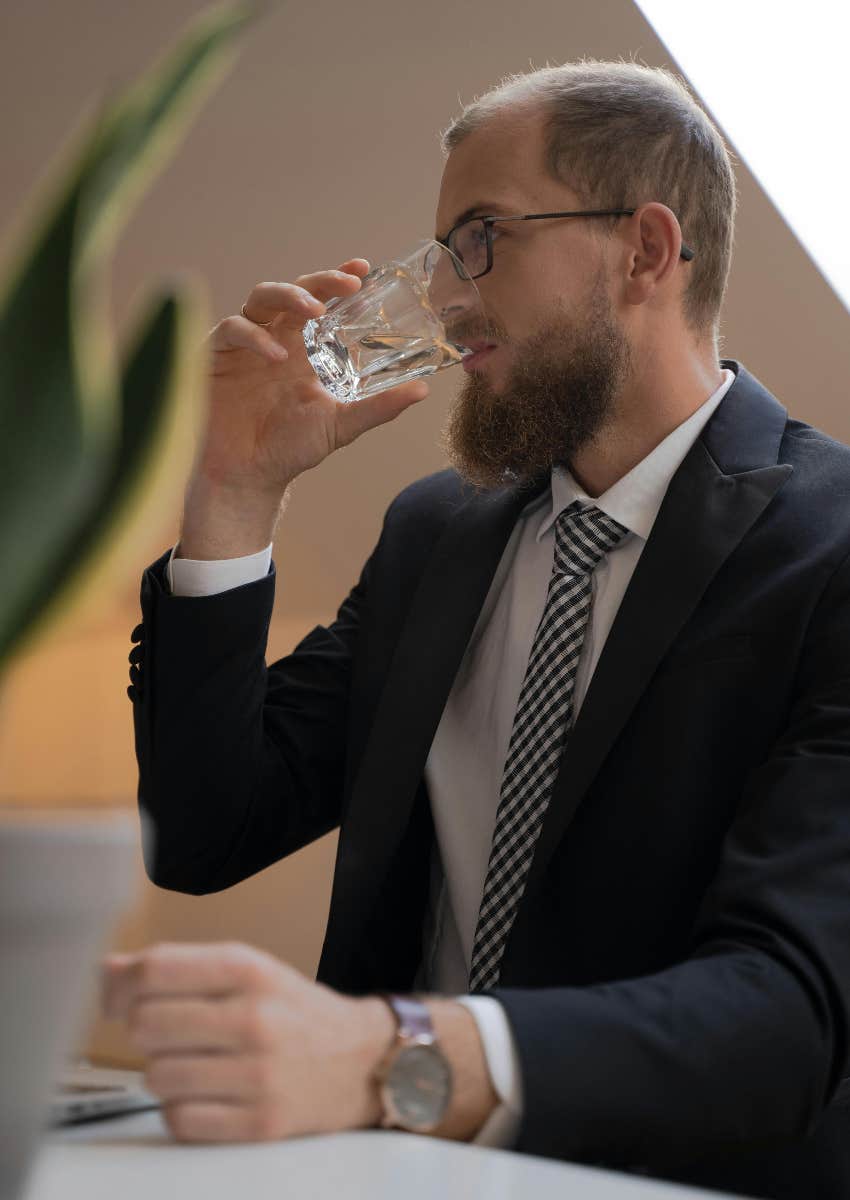 man in suit drinking a glass of water