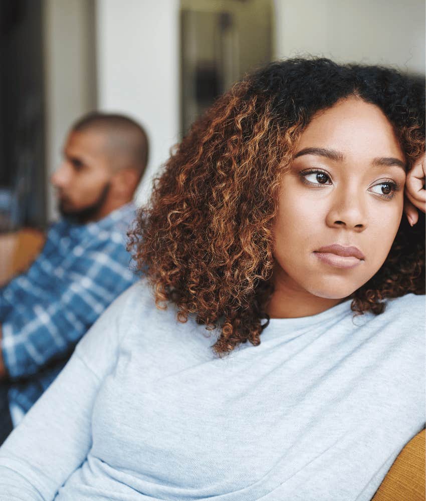 Upset woman rests head on fist while quiet man sits in background