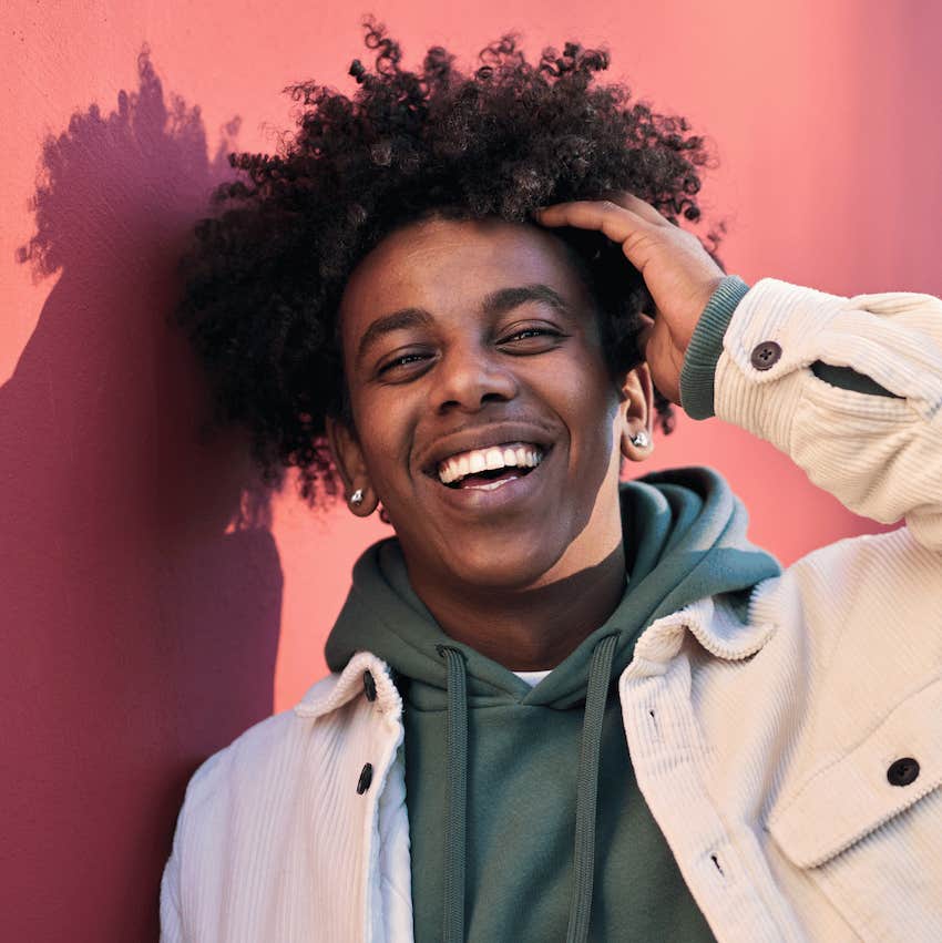 Smiling man touches his hair