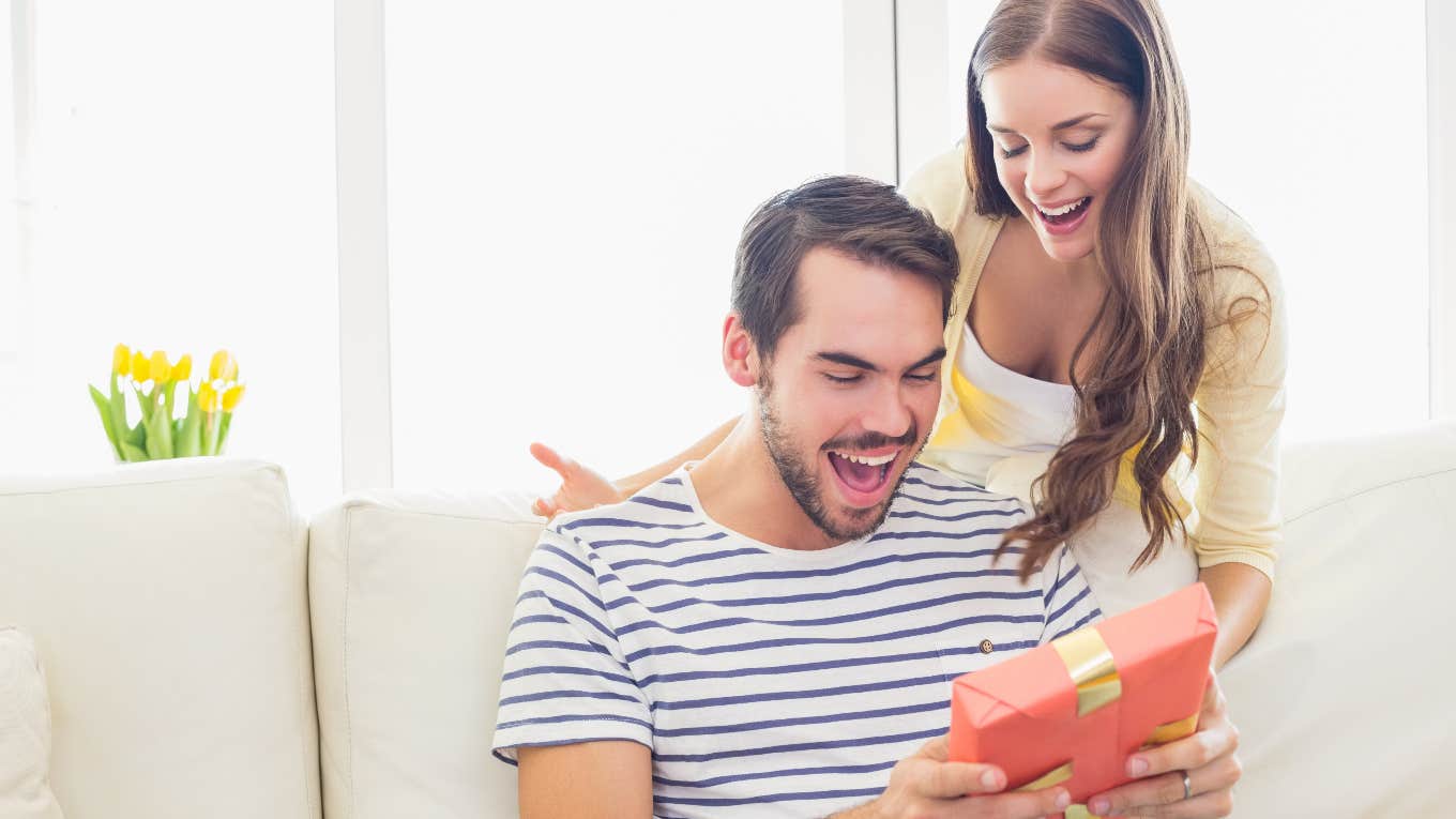 woman surprising man with a wrapped gift