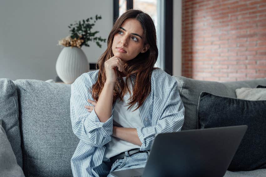 woman thinking with laptop in couch