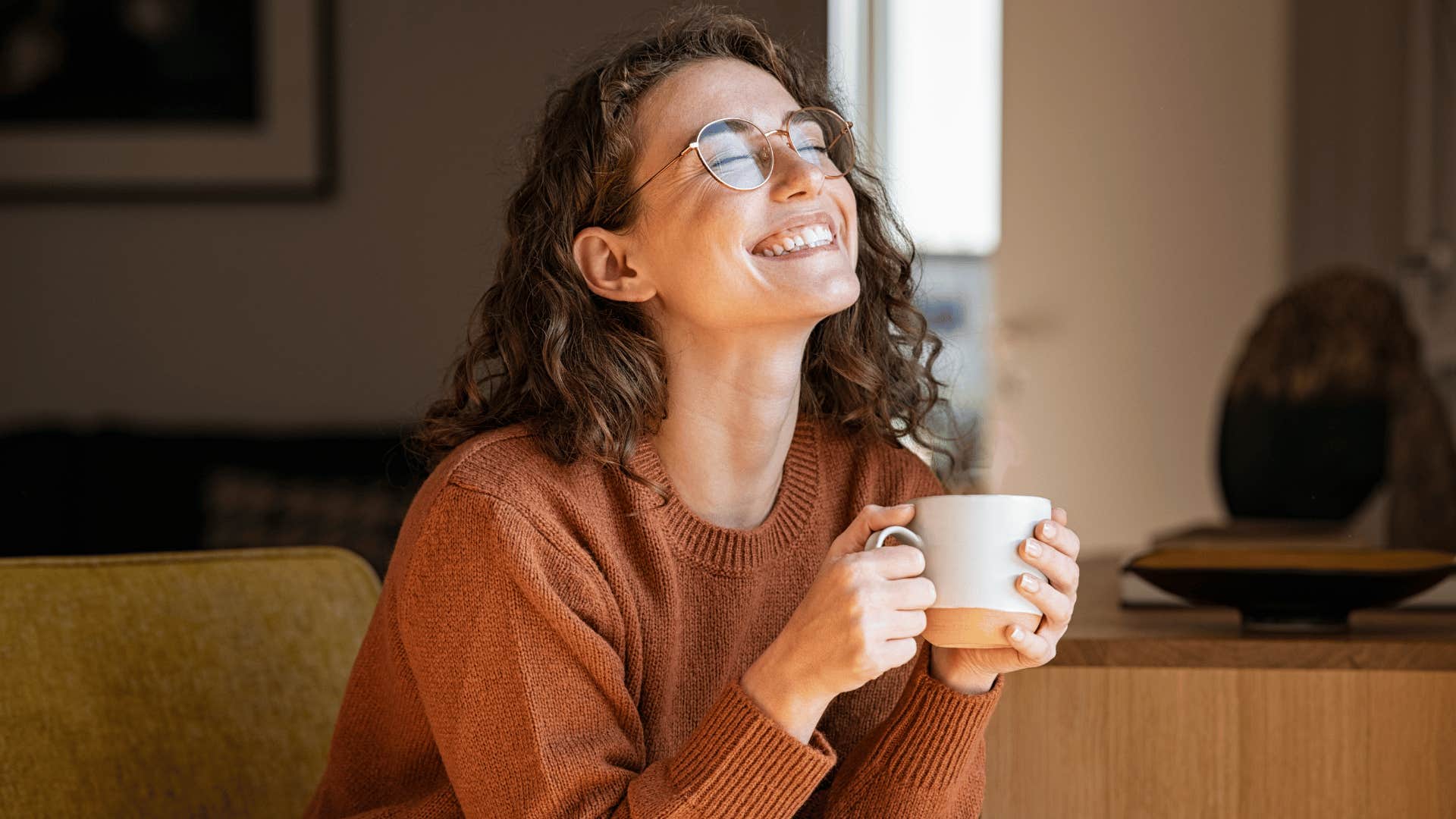 woman smiling while drinking coffee