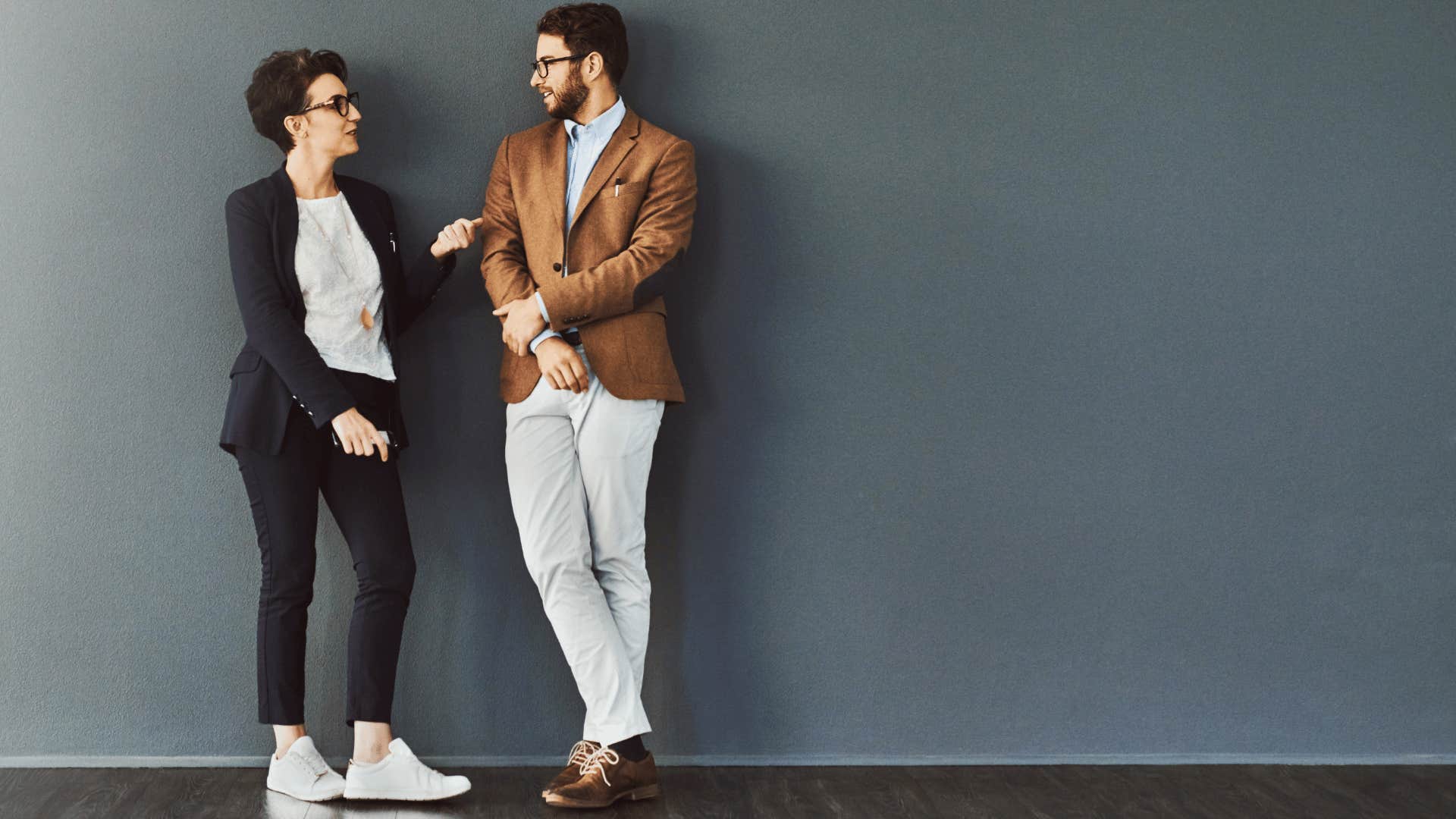 woman and man leaning against wall talking